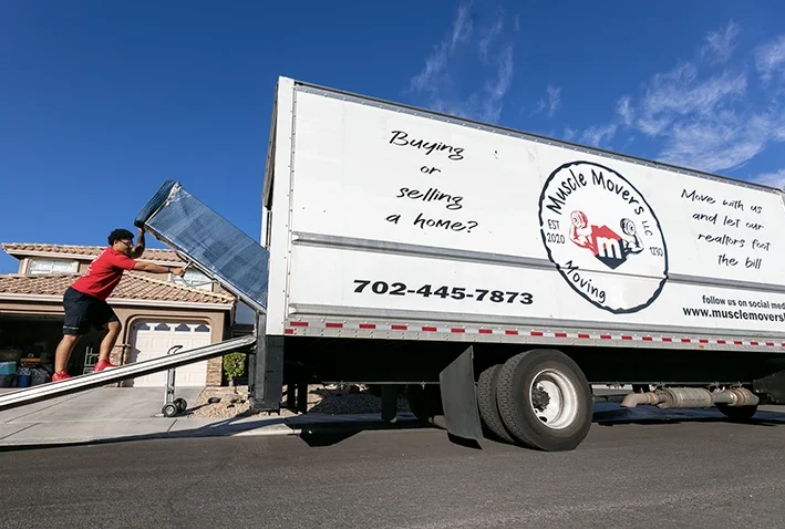 Moving truck loading furniture on residential street.