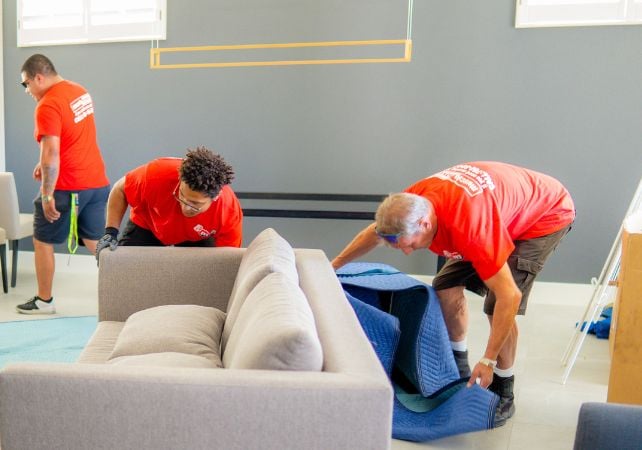 Movers wrapping couch with protective blanket