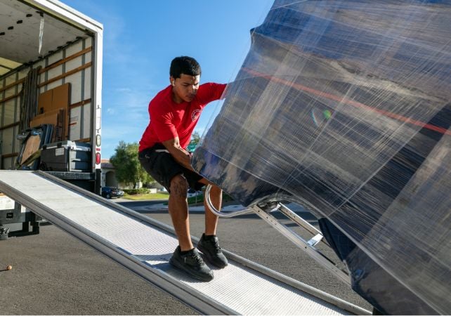 Worker moves packaged item on truck ramp.
