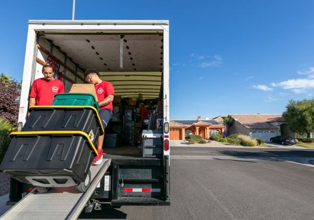 Movers unloading truck in residential neighborhood.