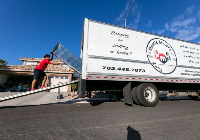 Mover loading truck outside home on sunny day.
