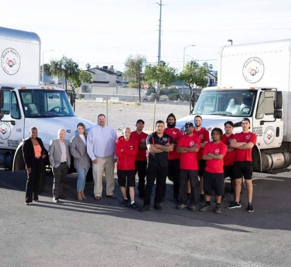Team posing in front of delivery trucks.