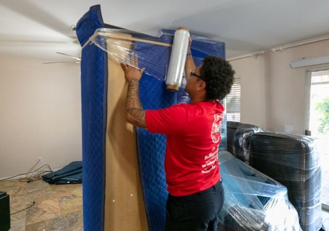 Mover wrapping furniture in protective material.