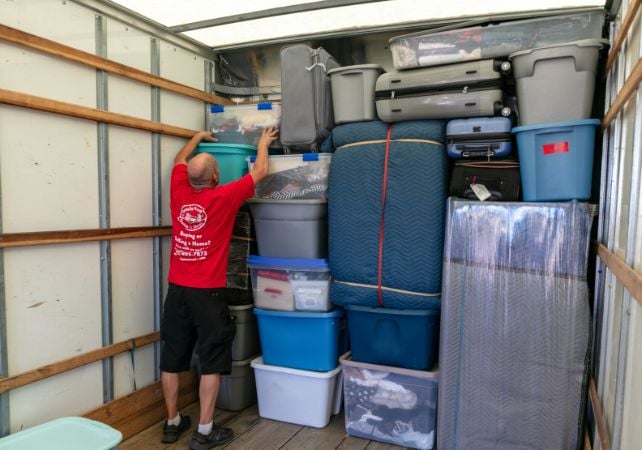 Man organizing boxes in a moving truck.