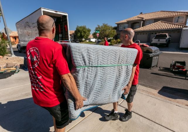 Movers carrying furniture into a truck on driveway.